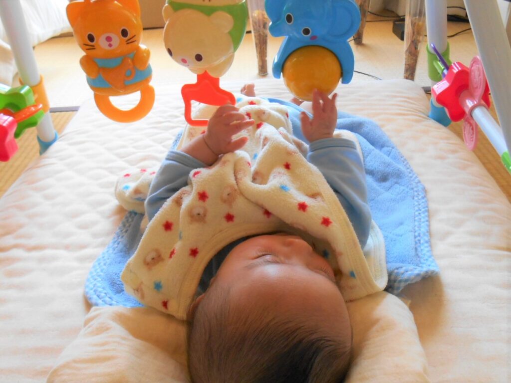 ガラガラに手をのばす赤ちゃん画像