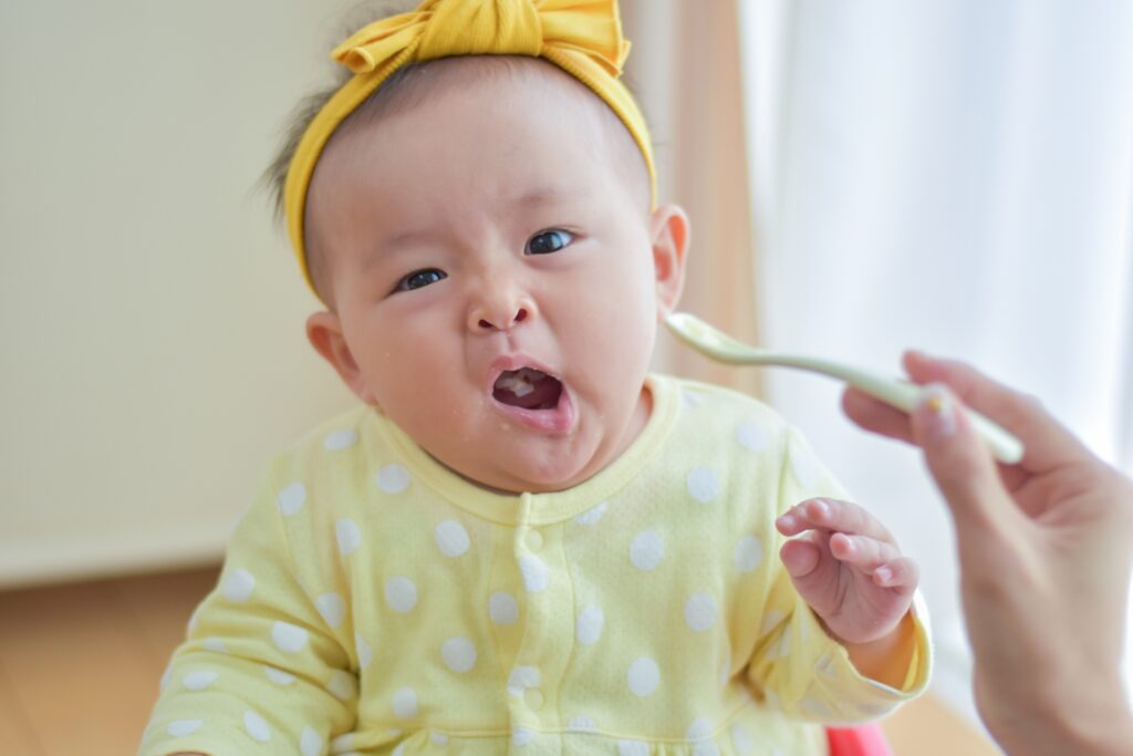 離乳食を含み顔のゆがむ赤ちゃん画像
